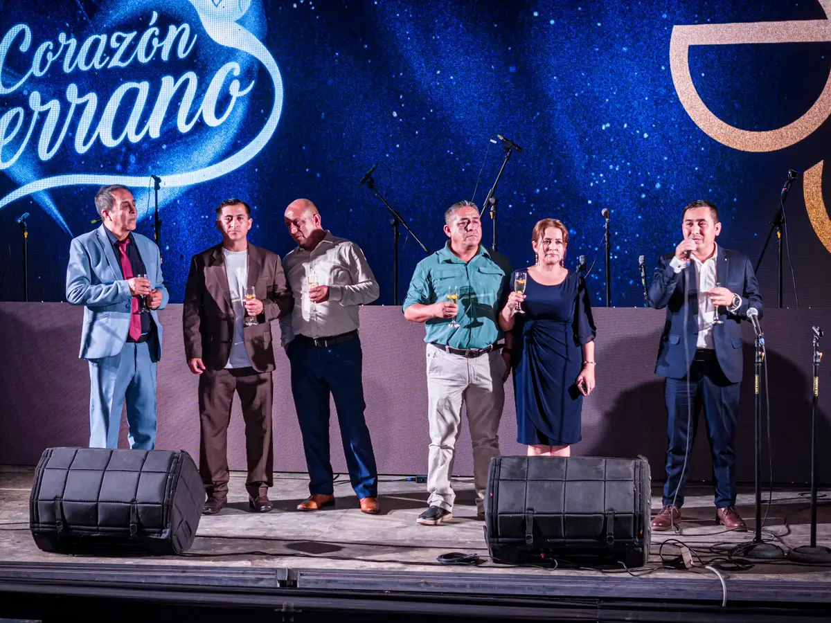 Directivos brindando sobre el escenario durante un aniversario institucional