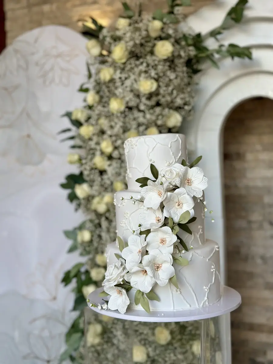 Torta de bodas decorada con flores blancas frente a un fondo floral