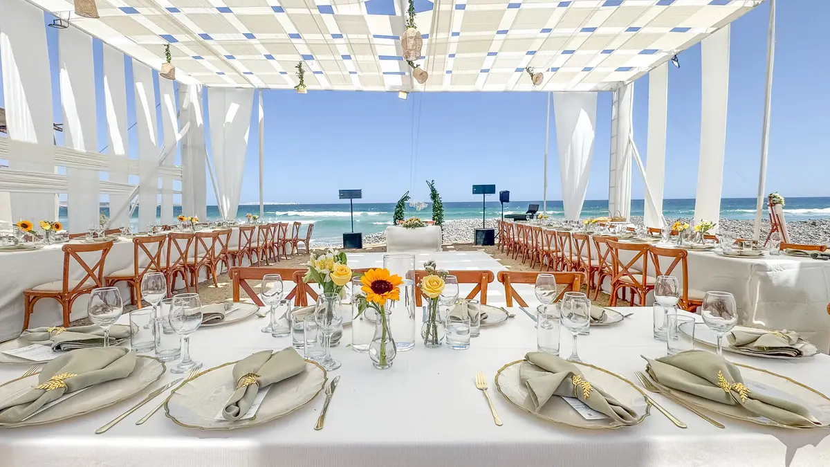 Montaje de boda bajo toldo, con mesas frente al mar