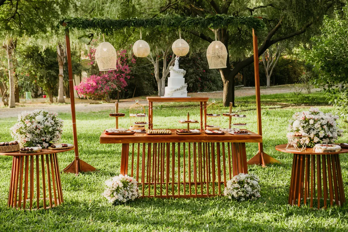 Mesa de bocaditos al aire libre con flores y faroles
