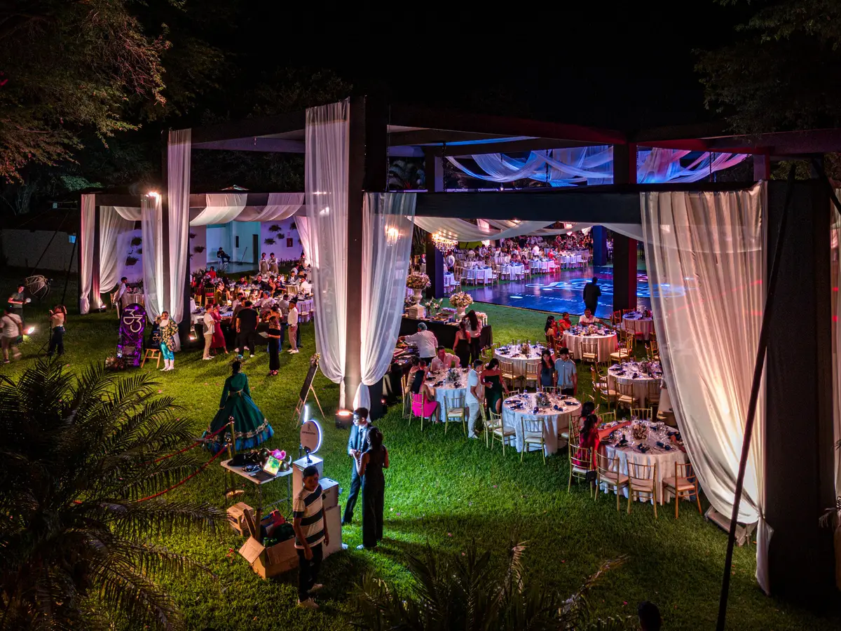 Montaje al aire libre con mesas, cortinas y luces cálidas