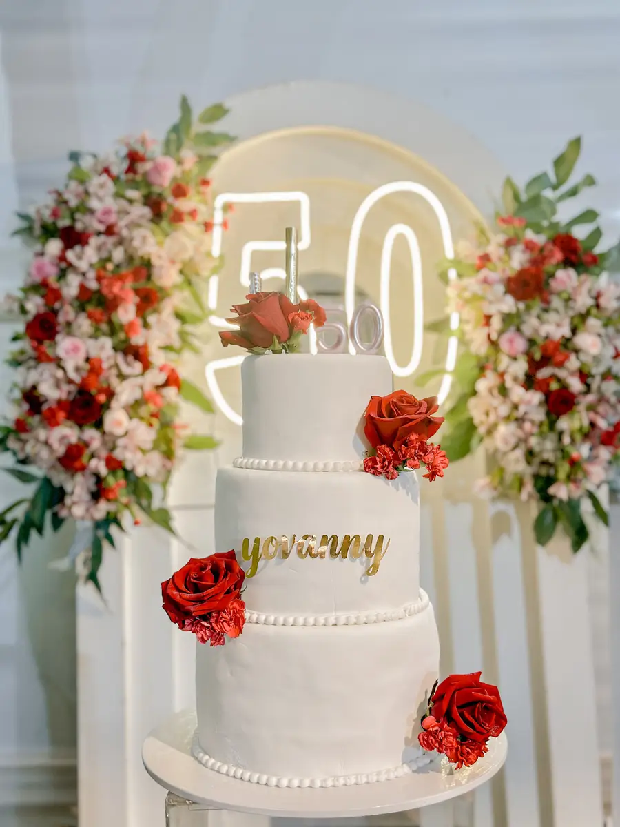 Torta decorada con rosas rojas frente a un fondo floral