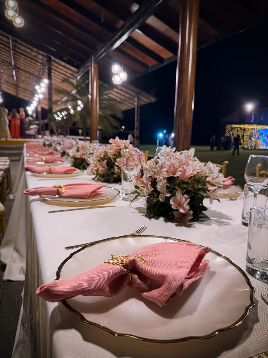 Mesa bajo el toldo, decorada con flores y detalles en rosa