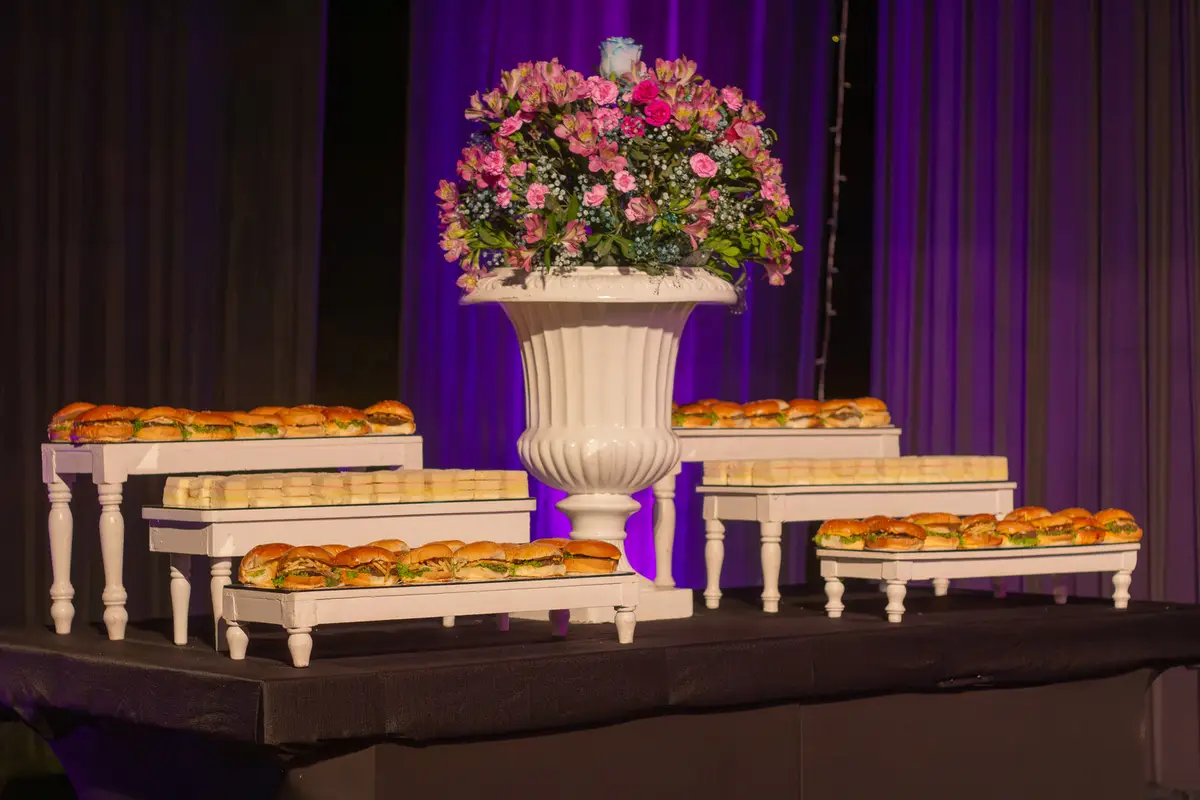 Mesa de bocaditos con arreglo floral y luces moradas