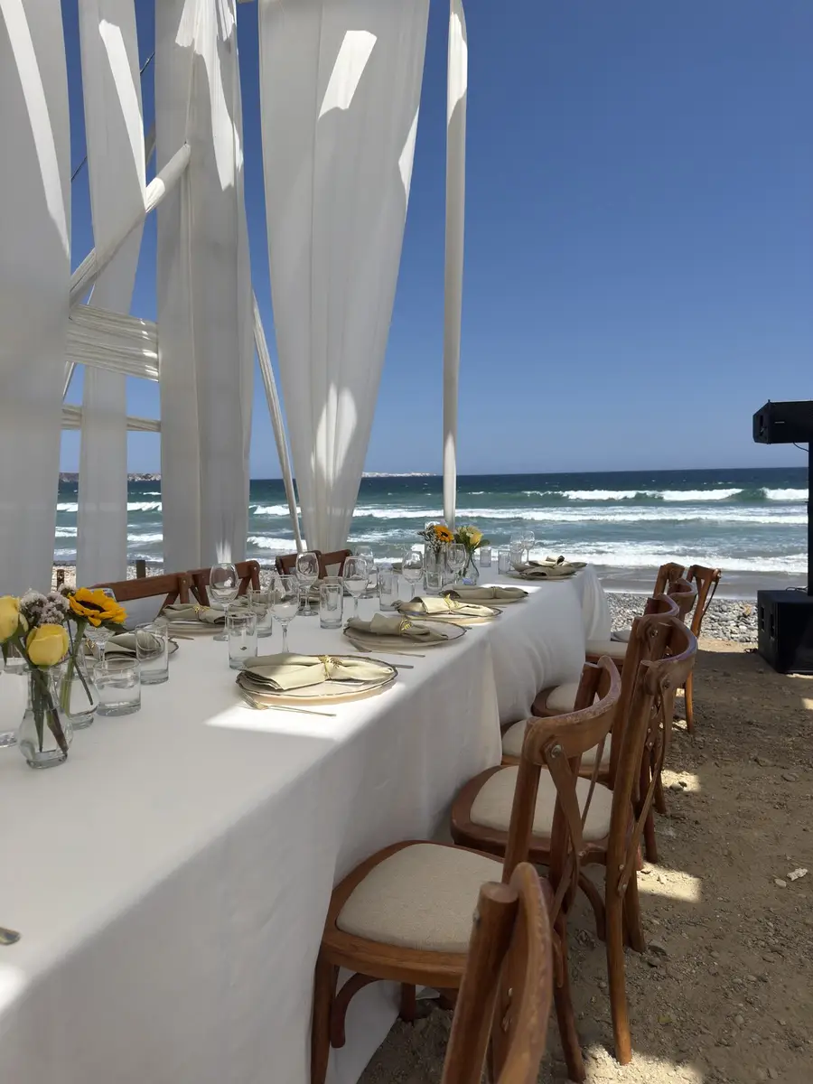 Mesa de boda frente al mar con flores y sillas de madera