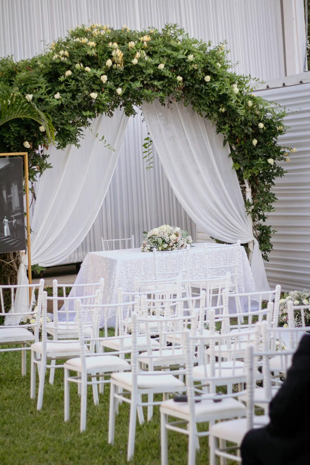 Ceremonia al aire libre con arco floral y sillas blancas