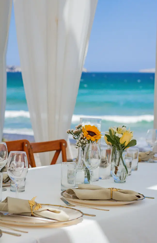 Mesa puesta frente al mar con flores amarillas