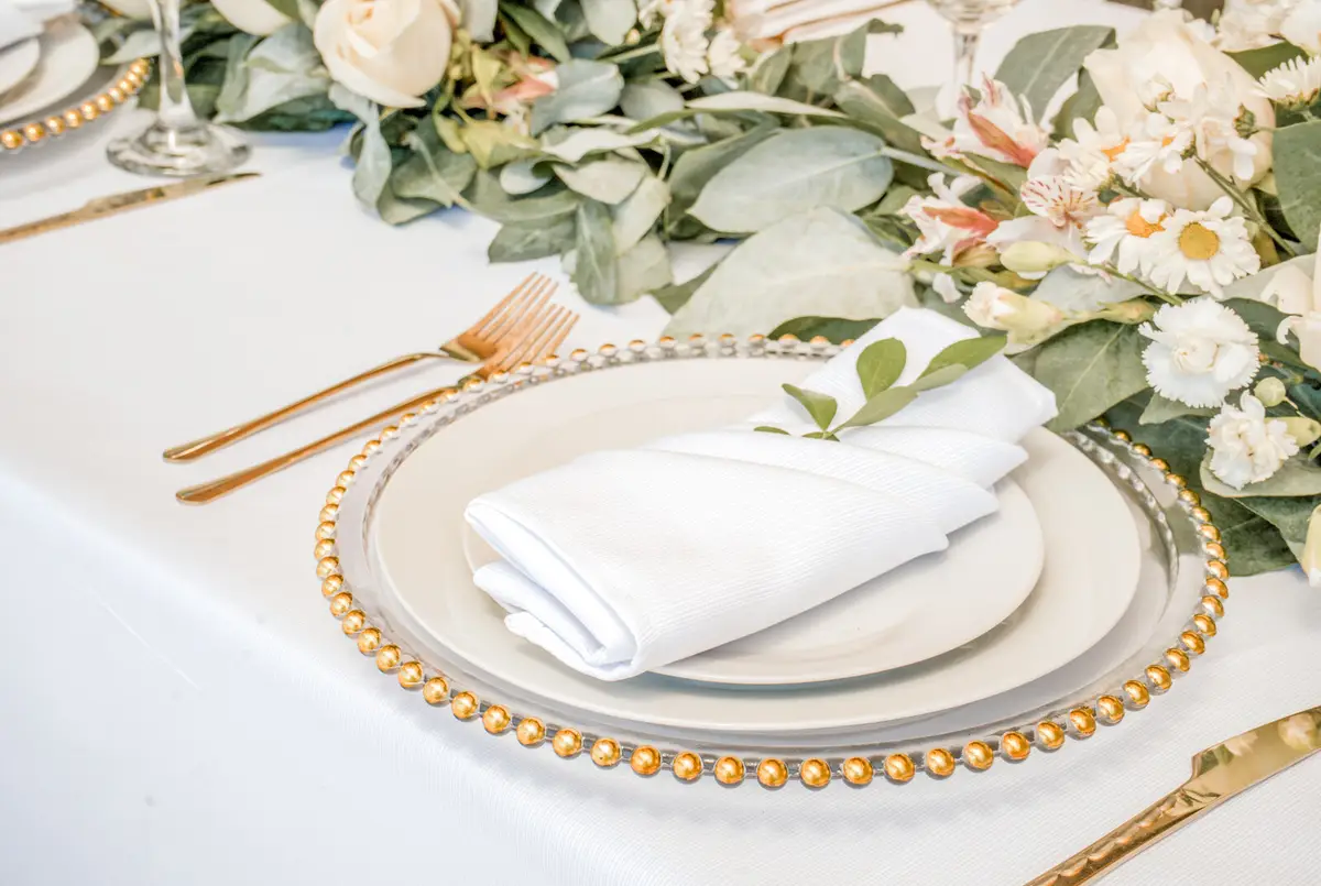 Detalle de mesa con vajilla, servilleta y flores en tonos suaves