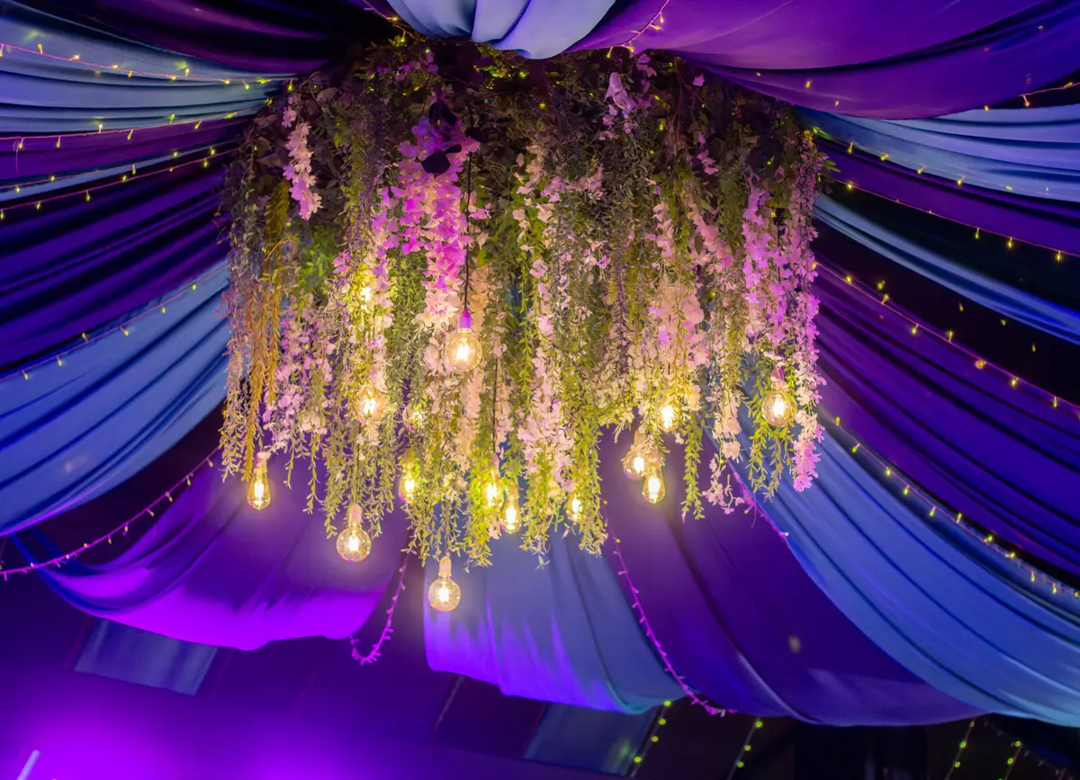 Arreglo floral colgante bajo un toldo de telas moradas y azules