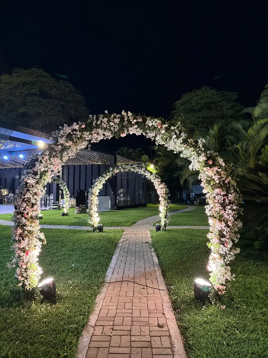 Camino de jardín enmarcado por arcos florales iluminados