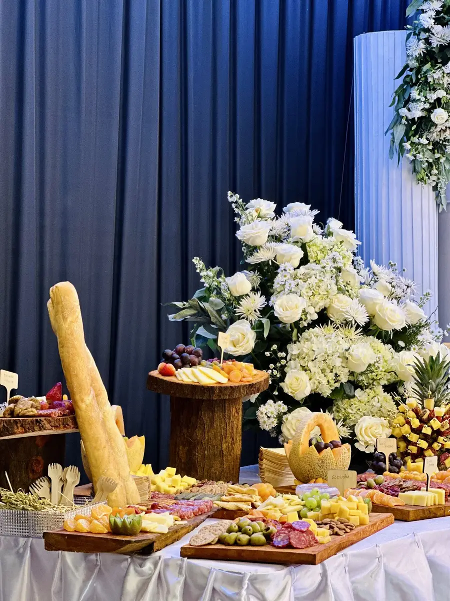 Mesa de quesos y bocaditos acompañada de abundantes flores blancas