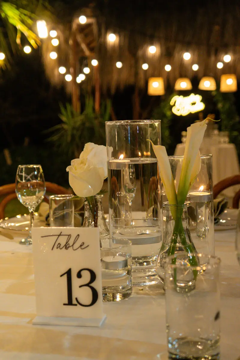 Mesa de boda con cristalería, velas y luz cálida bajo los árboles