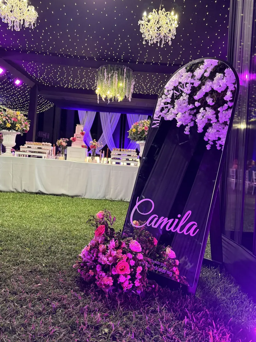Espejo de bienvenida con el nombre de la quinceañera entre flores, bajo el toldo iluminado