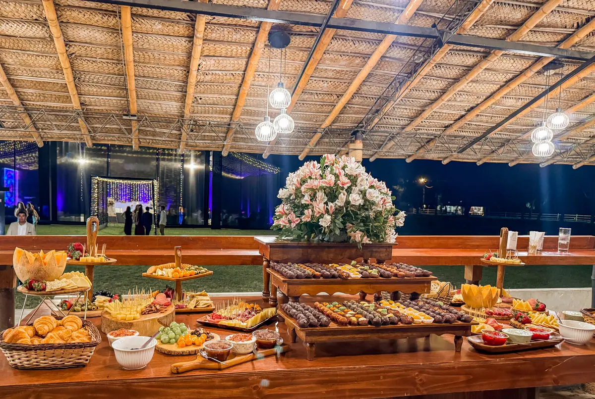 Mesa de bocaditos y postres bajo un cálido techo de paja